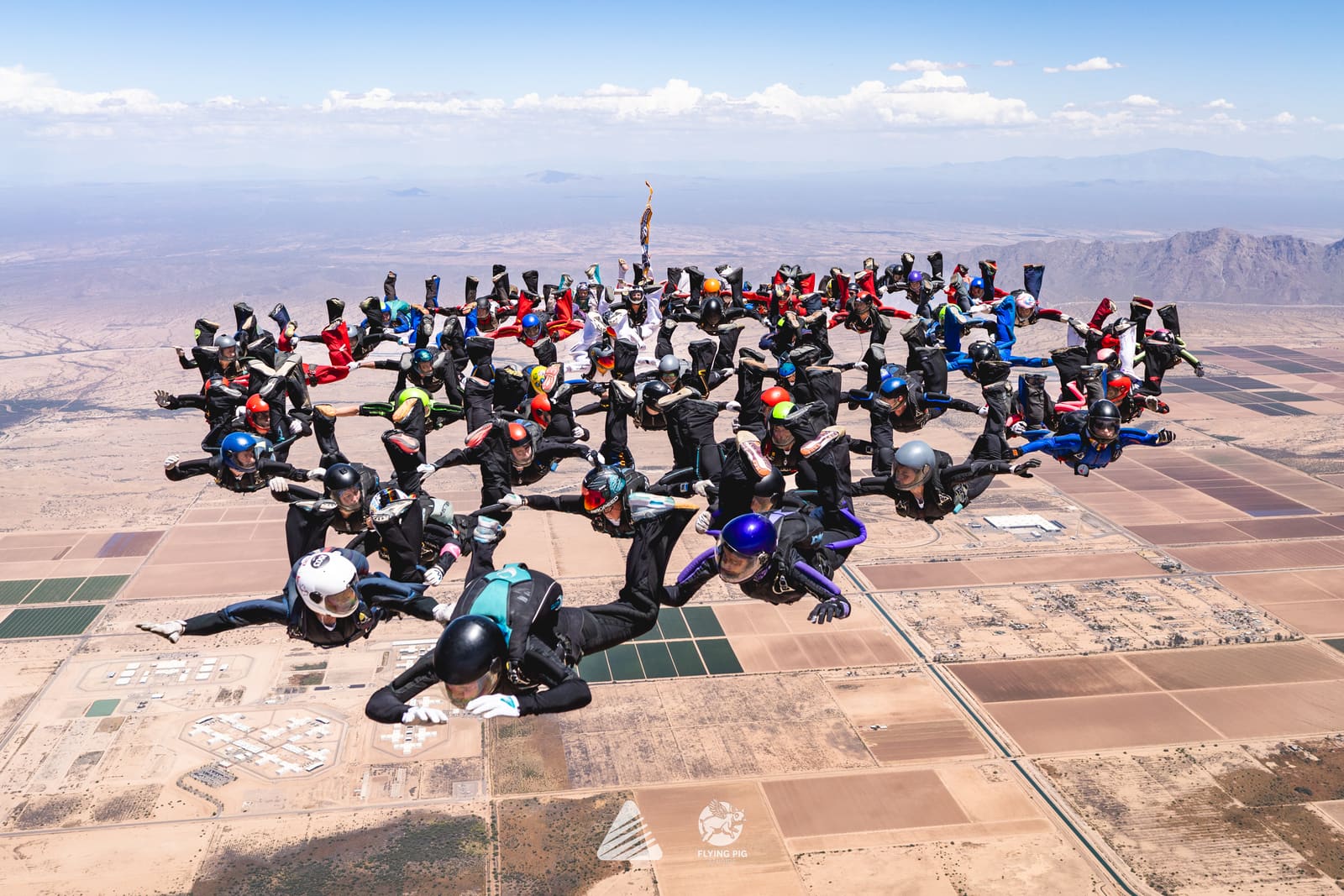 Large group of skydivers gathered in formation above the Arizona desert